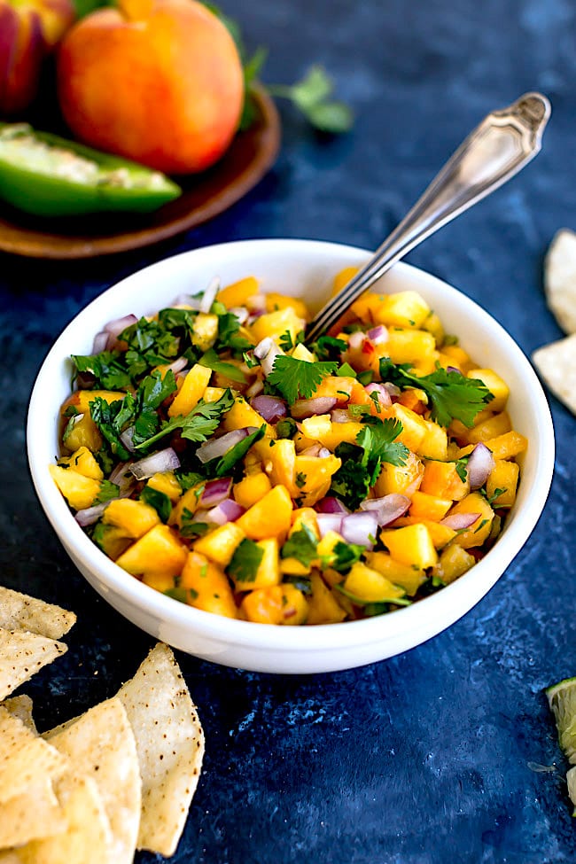 Peach Salsa Is An Easy Summer Snack That Can Be Made In Minutes. Serve The Salsa With Chips Or Use The Salsa As A Topping For Tacos, Grilled Chicken, Fish, Or Pork. This Salsa Recipe Is A Summer Favorite! #peach #salsa #easyrecipe #glutenfree #vegan #vegetarian #summer Easy Peach Salsa in a bowl with spoon