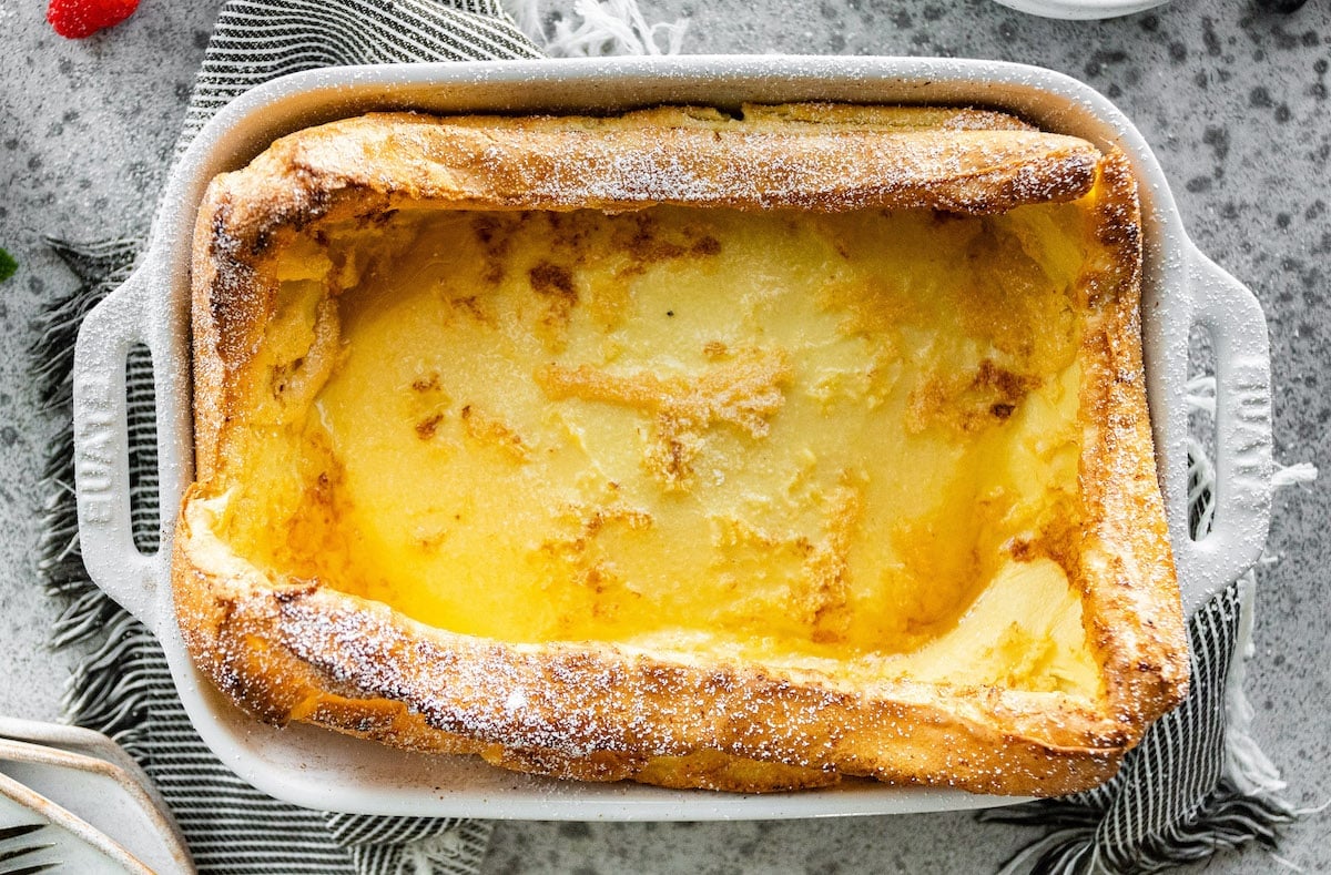 German pancakes in baking dish dusted with powdered sugar. 
