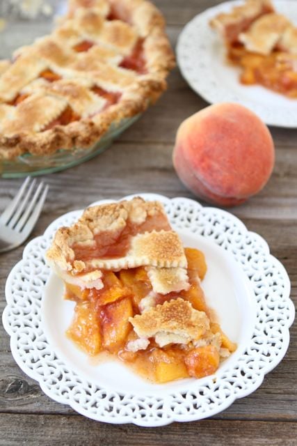 Peach Pie Recipe from www.twopeasandtheirpod.com #pie #recipe Peach pie slice with peach pie filling on plate