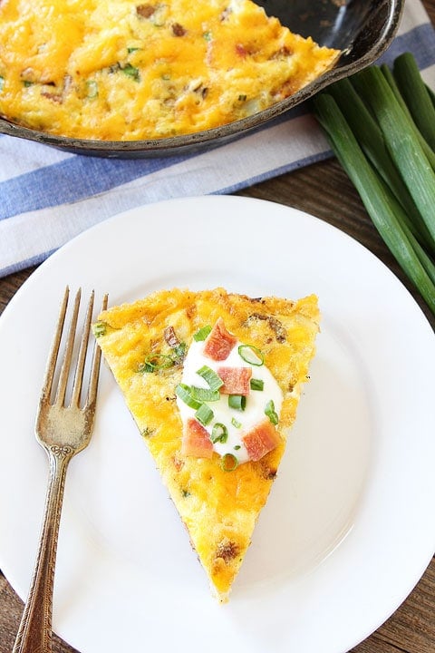 Loaded Baked Potato Frittata-all of your favorite potato toppings in a frittata! Recipe on www.twopeasandtheirpod.com Potato Frittata slice with sour cream and onions on top