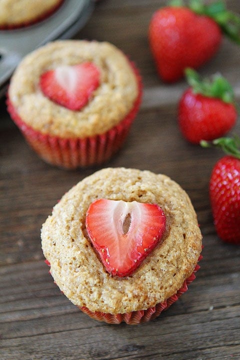 Whole Wheat Strawberry Banana Muffins Recipe on twopeasandtheirpod.com. Kids and adults love these quick and easy muffins! #recipe #breakfast Whole Wheat Banana Muffins in red baking cups with strawberries on top