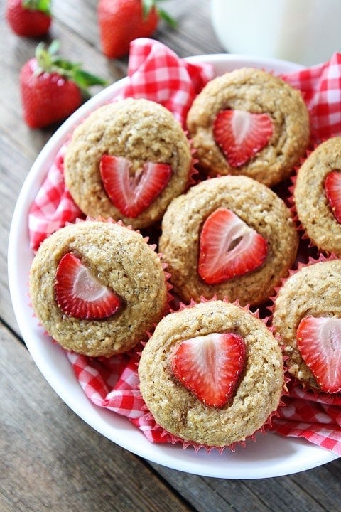 Whole Wheat Strawberry Banana Muffins Recipe on twopeasandtheirpod.com. Love these quick and easy muffins! #breakfast #muffins whole wheat banana muffins with strawberries on top piled in bowl