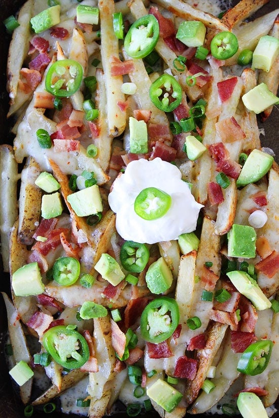 Loaded Cheese Fries Recipe on twopeasandtheirpod.com Baked fries that are loaded with cheese, bacon, avocado, jalapeño, and sour cream! Perfect for game day or any day! Loaded Cheese Fries Recipe