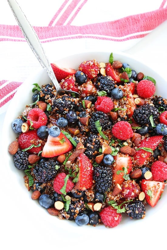 Berry Quinoa Salad Recipe on twopeasandtheirpod.com This healthy fruit salad is loaded with berries and has a simple citrus dressing! It is a summer favorite! Berry Quinoa Salad in bowl with spoon.