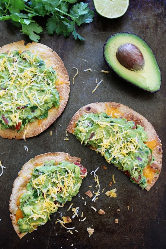 Cheesy Guacamole Tostadas Recipe on twopeasandtheirpod.com These easy and cheesy tostadas are perfect for an easy dinner or snack! Kids and adults love them! Vegetarian Tostadas garnished with cilantro