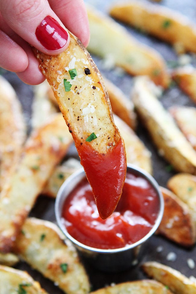 Baked Garlic Parmesan Potato Wedges Recipe on twopeasandtheirpod.com These easy baked fries are the BEST! They are crispy and great as an appetizer or side dish! Parmesan Potato Wedges dipped in ketchup