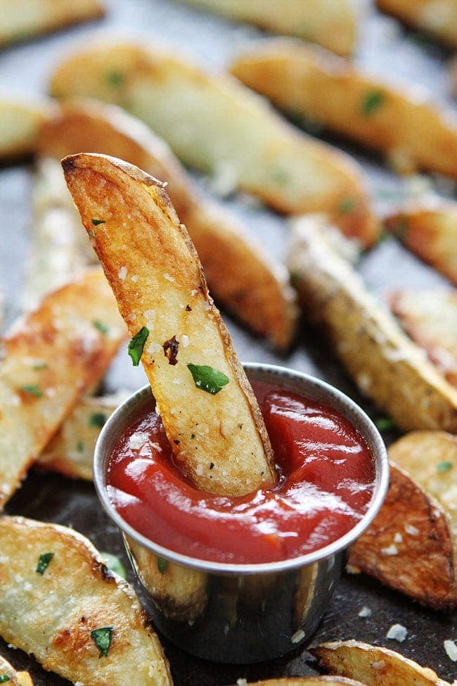 Baked Garlic Parmesan Potato Wedges Recipe on twopeasandtheirpod.com These easy baked oven fries are our favorite! They are great as an appetizer or served along side any meal! Baked Potato Wedges dipped in ketchup