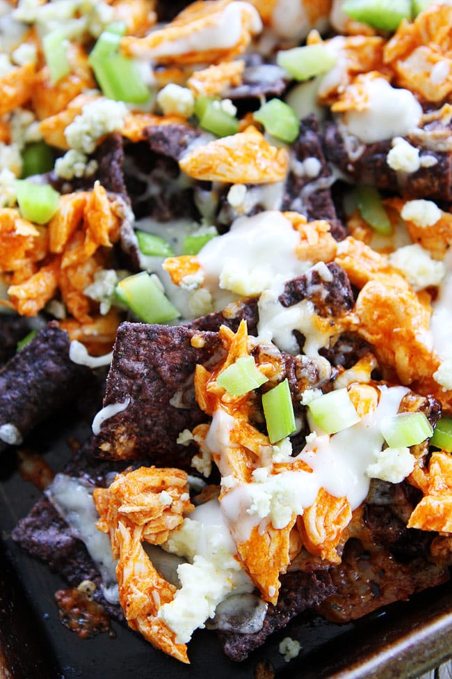 Buffalo Chicken Nachos Recipe on twopeasandtheirpod.com Cheesy nachos topped with spicy buffalo chicken, blue cheese, and celery! Everyone LOVES these nachos! Buffalo Chicken Nachos Recipe