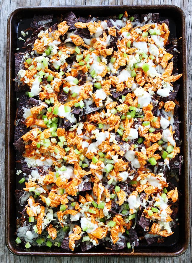 Buffalo Chicken Nachos Recipe on twopeasandtheirpod.com Cheesy nachos topped with spicy buffalo chicken, blue cheese, and celery! The perfect game day food! Buffalo Chicken Nachos Recipe