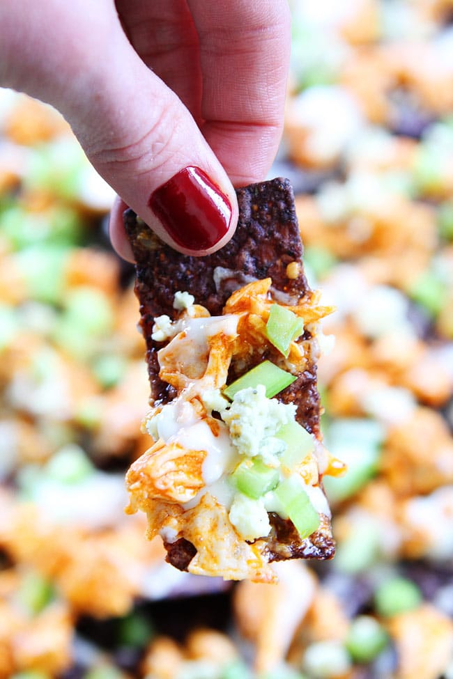 Buffalo Chicken Nachos Recipe on twopeasandtheirpod.com Cheesy nachos topped with spicy buffalo chicken, blue cheese, and celery! The ultimate game day snack! Buffalo Chicken Nachos Recipe