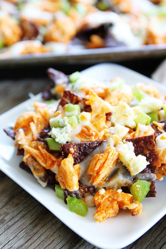 Buffalo Chicken Nachos Recipe on twopeasandtheirpod.com Cheesy nachos topped with spicy buffalo chicken, blue cheese, and celery! The perfect game day food! Buffalo Chicken Nachos Recipe
