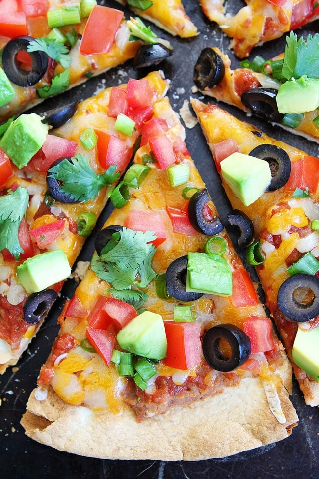 Crispy Mexican Tortilla Pizza Recipe on twopeasandtheirpod.com Make this easy pizza for dinner tonight. It only takes 15 minutes to make! Mexican Pizza topped with cilantro, onions, avocado, tomatoes and olives