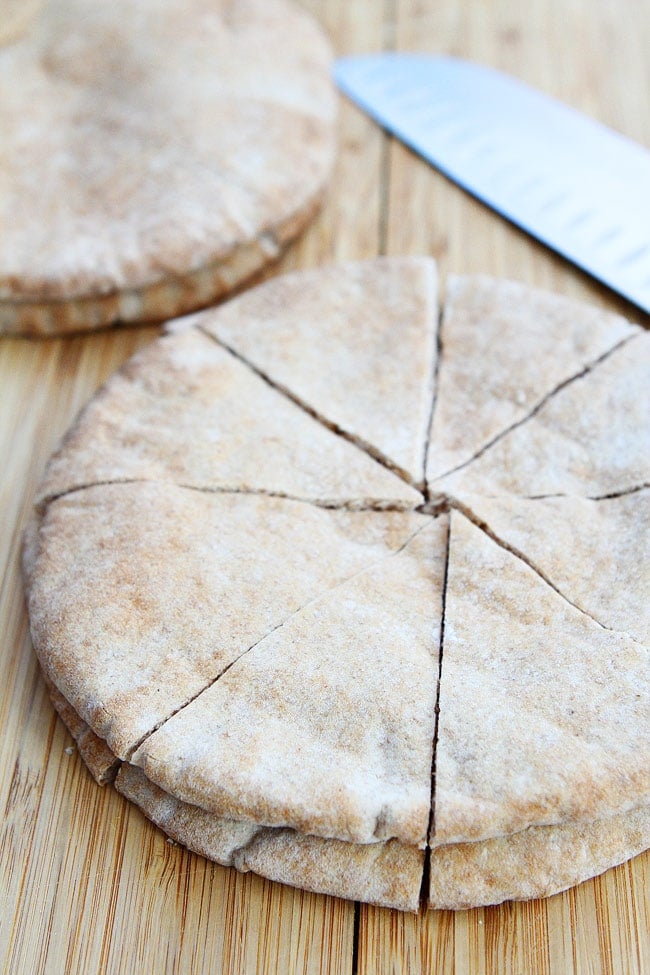 Homemade Pita Chips Recipe on twopeasandtheirpod.com Pita chips are easy to make at home! pita bread cut into triangles on wood cutting board.