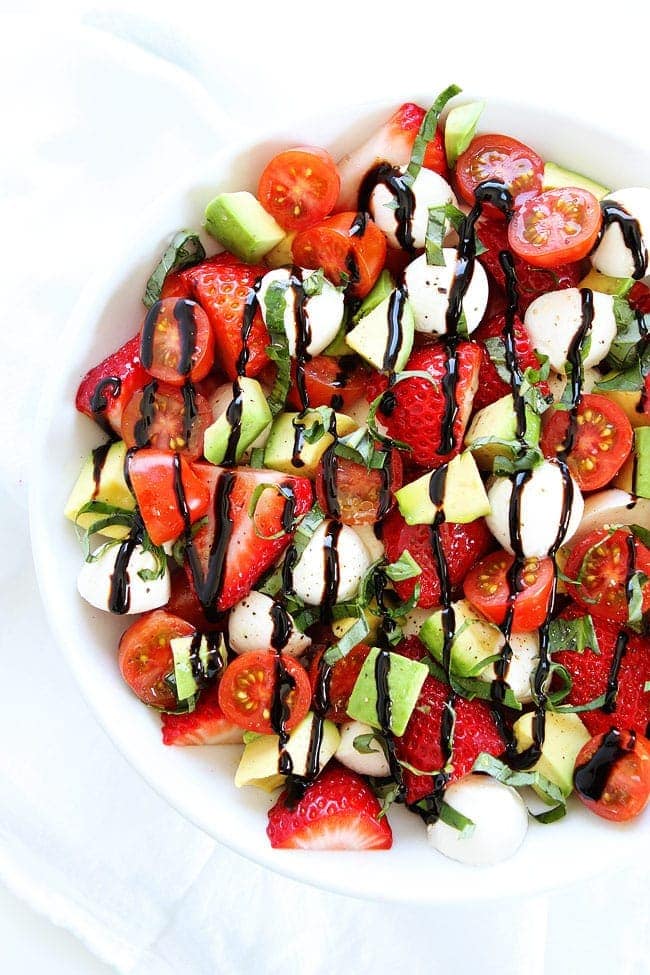 Avocado Strawberry Caprese Salad Recipe on twopeasandtheirpod.com This simple caprese salad is the perfect salad for spring! Avocado Caprese Salad with Strawberries in large bowl