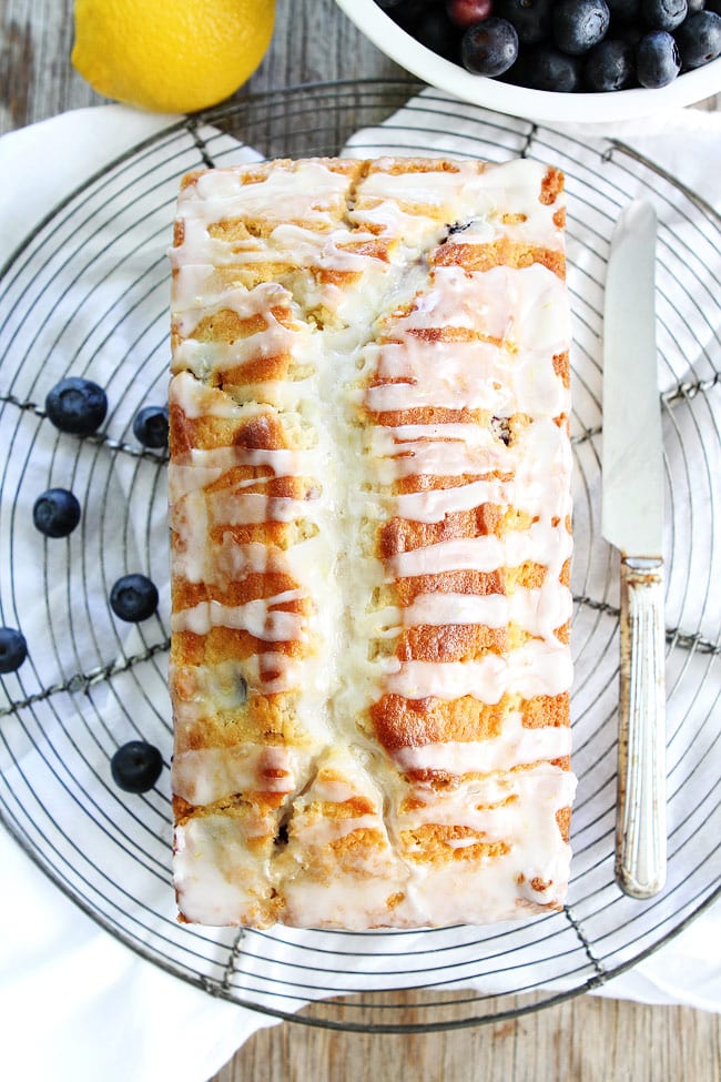 Lemon Blueberry Loaf Cake Recipe on twopeasandtheirpod.com This easy lemon loaf cake is bursting with blueberries! The sweet lemon glaze is the perfect finishing touch! Lemon Blueberry Bread On Plate To Cut