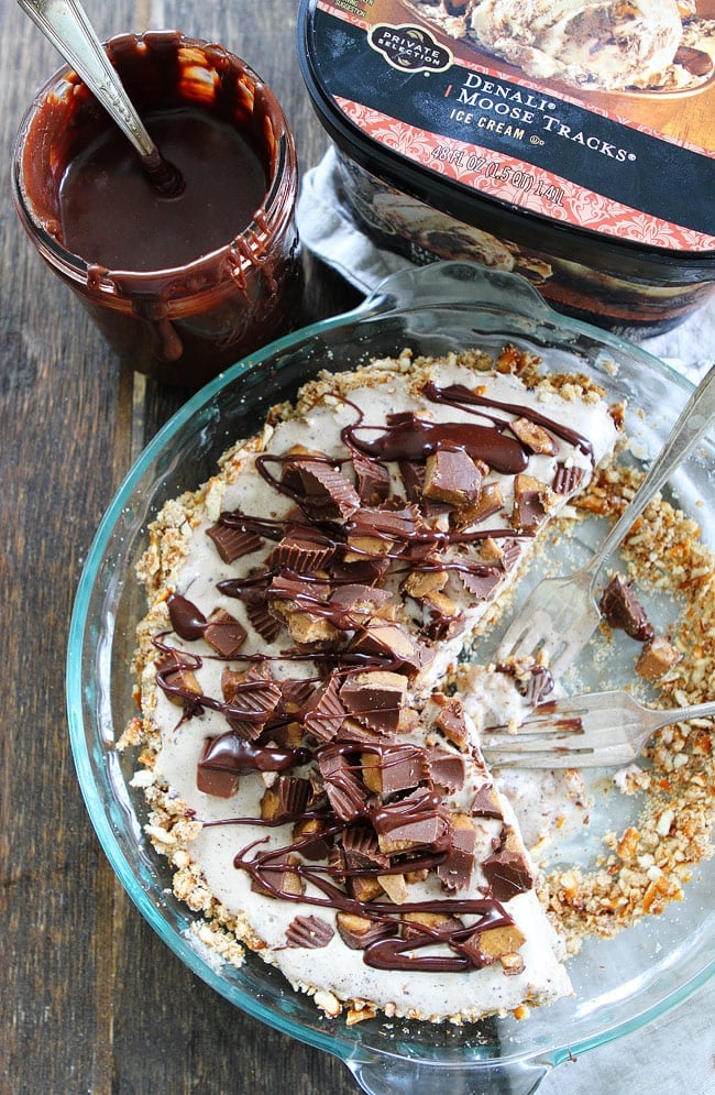 Peanut Butter Pretzel Ice Cream Pie Recipe on twopeasandtheirpod.com A salty pretzel crust filled with Moose Tracks ice cream then topped with peanut butter cups and drizzled with peanut butter hot fudge sauce! This easy pie recipe is going to be your new favorite dessert! Peanut Butter Pretzel Ice Cream Pie Recipe