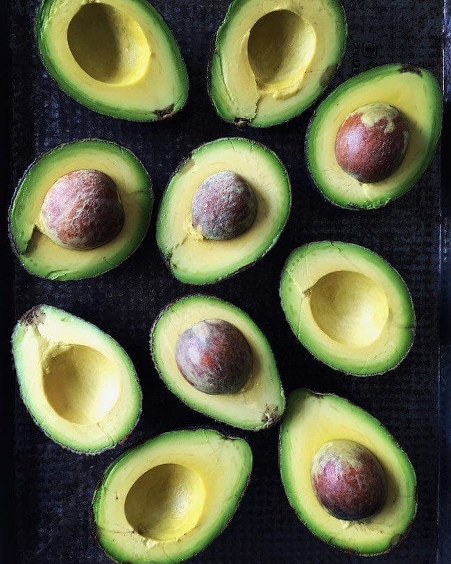 avocados cut in half on baking sheet.