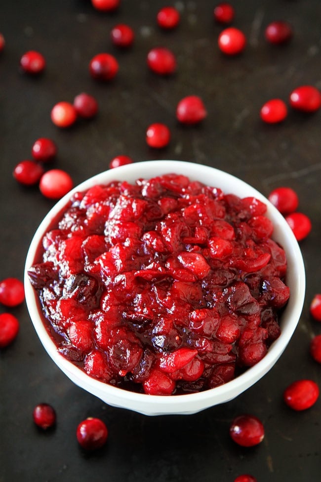 Maple Cranberry Sauce Recipe-Fresh cranberry sauce sweetened with pure maple syrup, orange zest, orange juice, and a hint of cinnamon. This is the BEST cranberry sauce recipe and it's SO easy to make! cranberry sauce in white bowl with fresh cranberries.