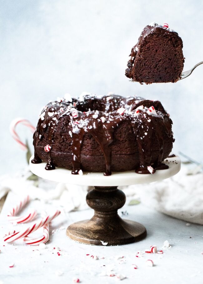Chocolate Peppermint Bundt Cake Recipe on twopeasandtheirpod.com Moist chocolate sour cream bundt cake drizzled with a silky smooth chocolate glaze and garnished with crushed peppermint candies. This cake is the perfect holiday dessert! a piece of cake being cut out of a chocolate peppermint bundt cake.