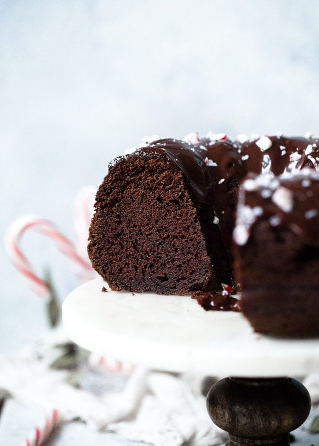 Chocolate Peppermint Bundt Cake Recipe on twopeasandtheirpod.com Moist chocolate sour cream bundt cake drizzled with a silky smooth chocolate glaze and garnished with crushed peppermint candies. This cake is the perfect holiday dessert! close up of chocolate peppermint bundt cake.