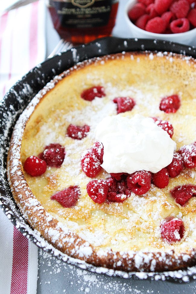 Raspberry Dutch Baby Pancake Recipe on twopeasandtheirpod.com This puffy baked pancake is dotted with fresh raspberries, dusted with powdered sugar, and topped with whipped cream. It is a real breakfast treat! Raspberry Dutch Baby Pancake in Pan