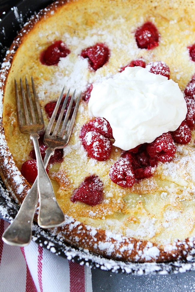 Raspberry Dutch Baby Recipe on twopeasandtheirpod.com This puffy baked pancake is a breakfast favorite and it's so easy to make! Raspberry Dutch Baby with whipped cream