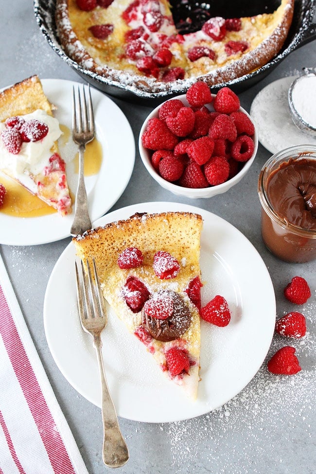 Raspberry Dutch Baby Recipe on twopeasandtheirpod.com This easy puffy baked pancake is dotted with fresh raspberries, dusted with powdered sugar, and topped with whipped cream. It is a real breakfast treat! Dutch Baby Pancakes with raspberries and chocolate