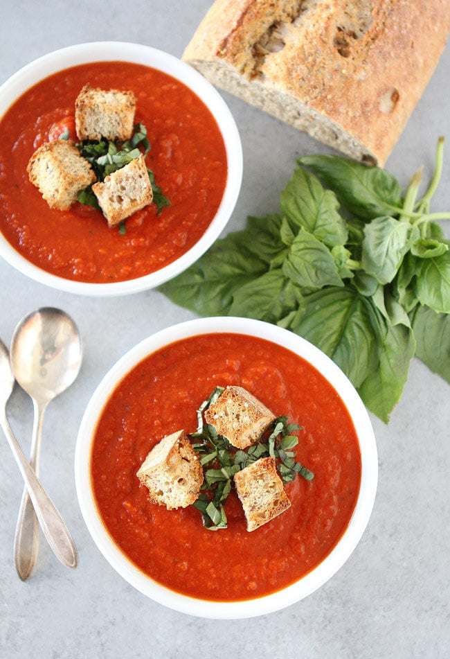 Roasted Red Pepper Tomato Soup Recipe on twopeasandtheirpod.com This easy and comforting tomato soup can be on the dinner table in under 30 minutes. Roasted Red Pepper Tomato Soup in bowls with croutons and fresh basil.
