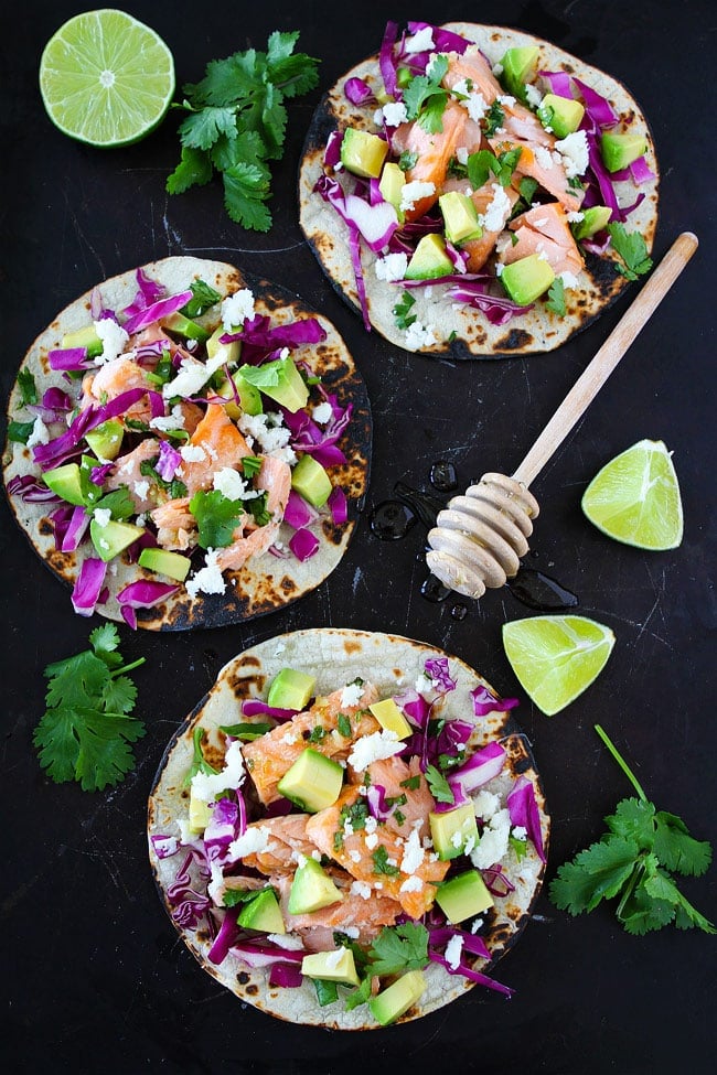 Honey Lime Salmon Tacos Recipe on twopeasandtheirpod.com These easy fish tacos take less than 30 minutes to make! They are perfect for Taco Tuesday or any day! Salmon tacos with red cabbage avocado and cheese