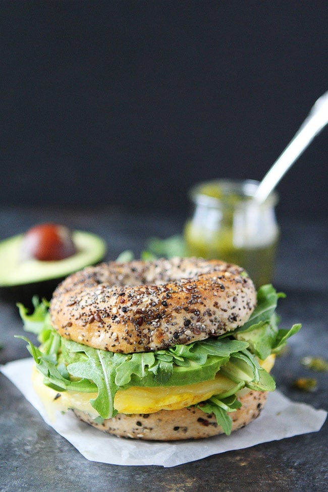 Egg, Avocado, and Pesto Bagel Sandwich with cheese and arugula. You will love this easy breakfast sandwich recipe. Egg, Avocado, and Pesto Bagel Sandwich with avocado and pesto.