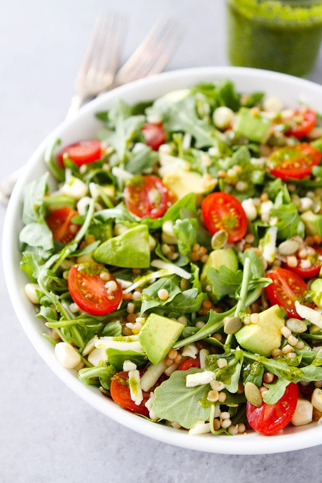 Summer Arugula Salad with couscous, avocado, corn, tomatoes, cheese, pepitas, and a simple basil vinaigrette. This fresh and simple salad makes goes great with any summer meal.