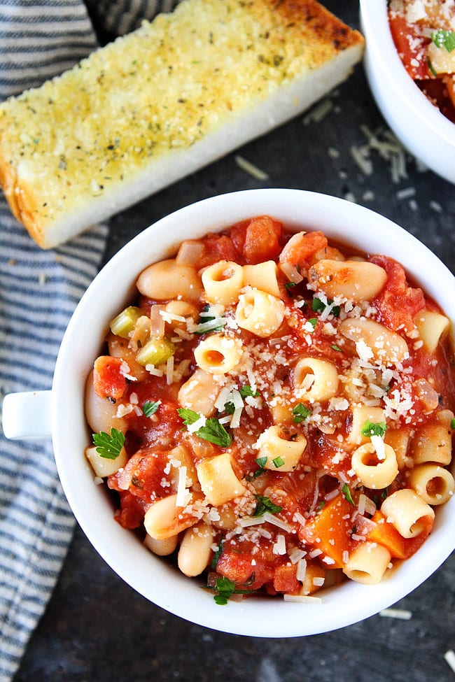 Pasta e Fagioli in bowlwith Parmesan cheese and garlic bread.