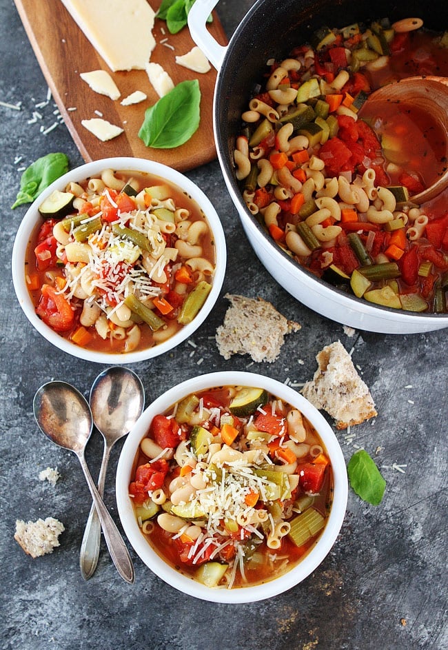 Minestrone Soup-this is the BEST Minestrone Soup Recipe. It is easy to make and perfect for a cold day! #minestrone #soup #vegetarian #healthyrecipes Minestrone soup in two white bowls and large white pot with crusty bread and spoons.