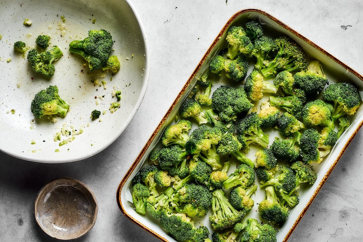 Easy roasted broccoli with garlic is destined to be your new go-to side dish! This crispy, oven-baked broccoli recipe is even kid-approved. Broccoli florets transferred from a bowl into a baking pan.