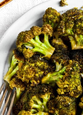 Close up of a bowl of roasted broccoli next to a fork.
