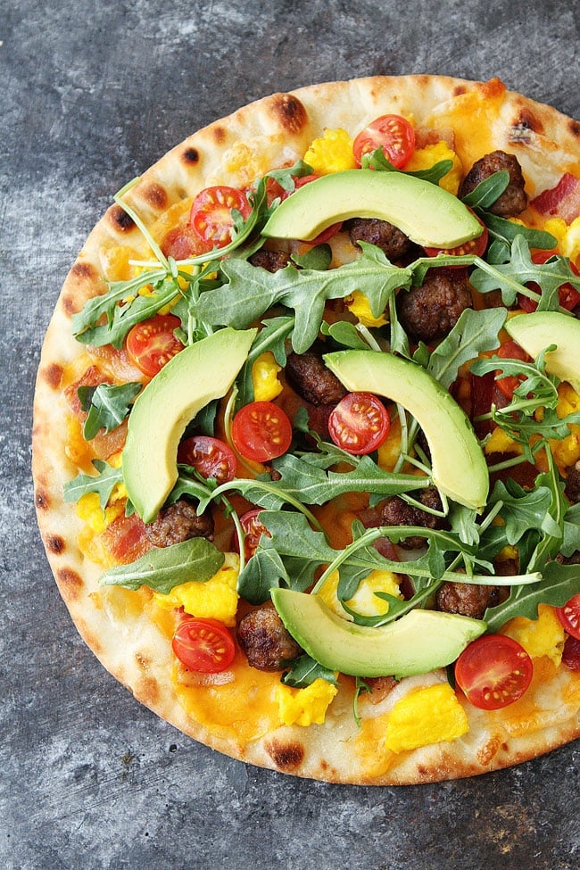 The Ultimate Breakfast Pizza with sausage, bacon, eggs, cheese, tomatoes, arugula, and avocado! #breakfastpizza #breakfast #pizza #easyrecipes #sausage #bacon #eggs #cheese Breakfast Pizza Recipe