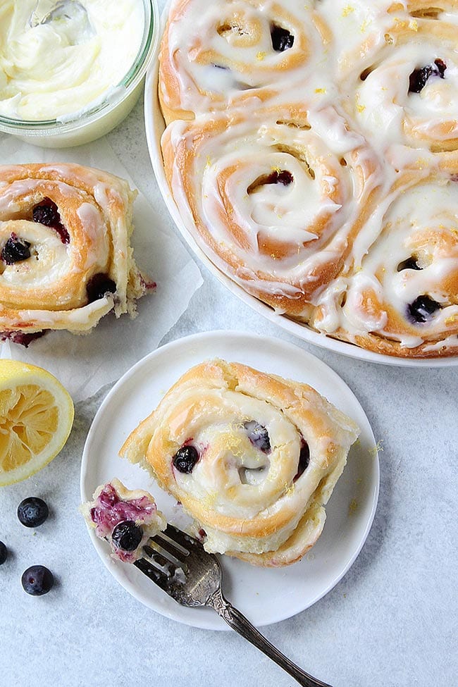 Lemon Blueberry Sweet Rolls Are Soft Sweet Rolls That Are Bursting With Fresh Blueberries And Covered In Lemon Cream Cheese Frosting. They Are The Perfect Treat For Breakfast Or Brunch. #lemon #blueberry #sweetrolls #breakfast #brunch #baking #creamcheese #holiday #dessert #yeast Lemon Blueberry Sweet Roll on plate
