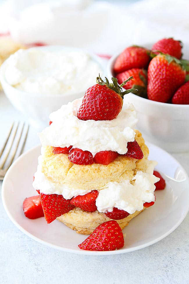 The BEST Strawberry Shortcake recipe! The perfect spring dessert! #dessert #strawberry #shortcake #strawbrerryshortcake Strawberry Shortcake with bowl of whipped cream and bowl of strawberries.