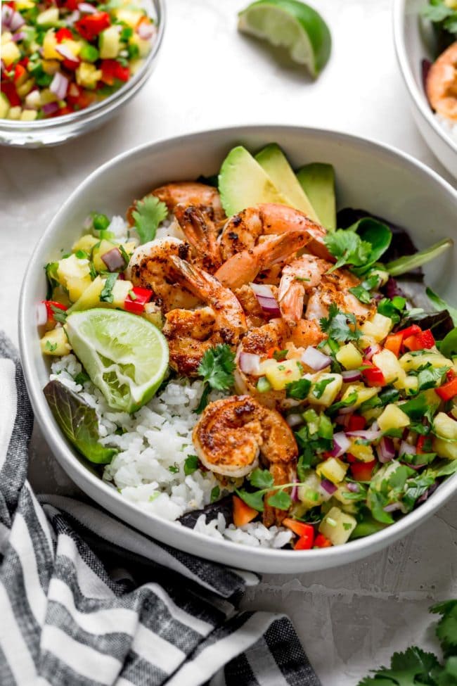 Shrimp Bowls With Coconut Cilantro Lime Rice And Pineapple Salsa Can Be On The Dinner Table In 30 Minutes! This Refreshing And Simple Meal Is A Summer Favorite! #shrimp #recipe #bowls #glutenfree #salsa #dinner #easydinner #shrimprecipe #healthyrecipe #easyrecipe #cooking Shrimp bowl with coconut lime rice, fresh pineapple salsa, avocado, and lime.
