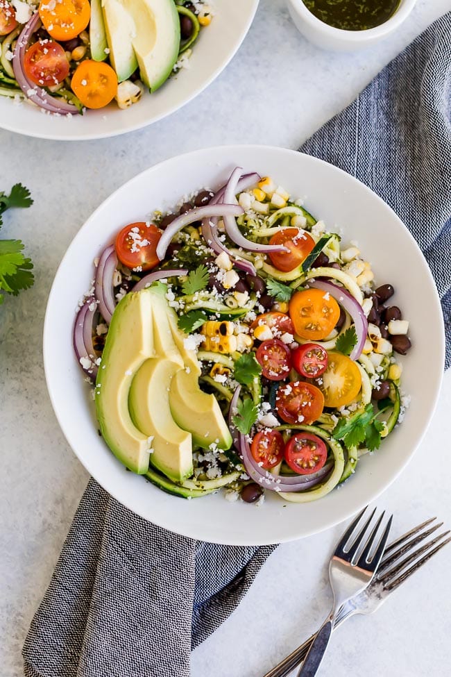 Southwestern Zucchini Noodle Bowls are a summer favorite meal! Zoodles With Black Beans, Charred Corn, Tomatoes, Avocado, And Cilantro Vinaigrette. You Will Love This Light And Refreshing Zucchini Noodle Recipe! Perfect For A Light Lunch Or Dinner! #zucchini #zoodles #zucchininoodles #vegetarian #vegan #glutenfree #easyrecipe #healthyrecipe #salad Southwestern Zucchini Noodle Bowls recipe
