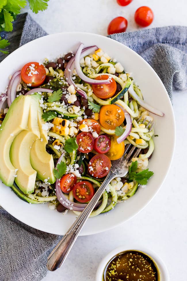 Southwestern Zucchini Noodle Bowls are a summer favorite meal! Zoodles With Black Beans, Charred Corn, Tomatoes, Avocado, And Cilantro Vinaigrette. You Will Love This Light And Refreshing Zucchini Noodle Recipe! Perfect For A Light Lunch Or Dinner! #zucchini #zoodles #zucchininoodles #vegetarian #vegan #glutenfree #easyrecipe #healthyrecipe #salad Southwestern Zucchini Noodle Recipe