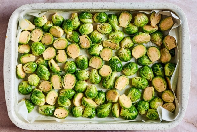 This roasted brussels sprouts recipe uses balsamic vinegar for an easy and flavorful Italian side dish that's healthy and vegetarian. A baking tray with a layer of parchment paper, full of uncooked, seasoned Brussels sprouts