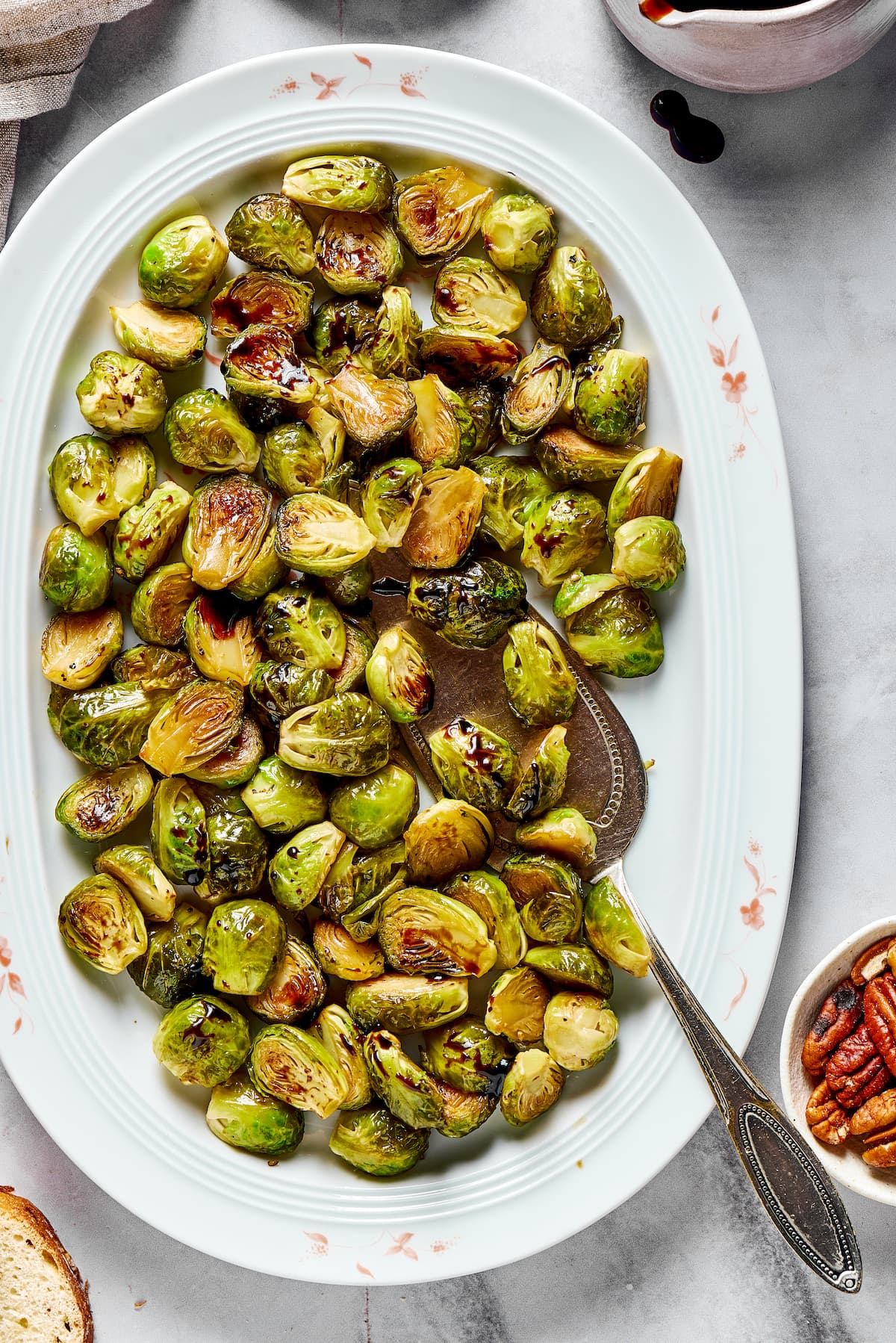 This roasted brussels sprouts recipe uses balsamic vinegar for an easy and flavorful Italian side dish that's healthy and vegetarian. A white oval tray full of roasted Brussels sprouts, with a serving spoon in it