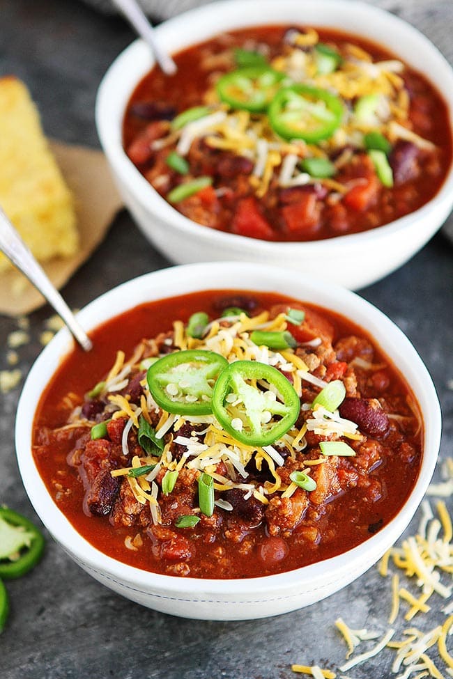 This easy Slow Cooker Beef Chili is a family favorite! Get out the crockpot and make it for dinner today! #chili #slowcooker #crockpot #dinner #easyrecipe #chilirecipe #fall #winter #gameday #glutenfree slow cooker chili in bowls with toppings.