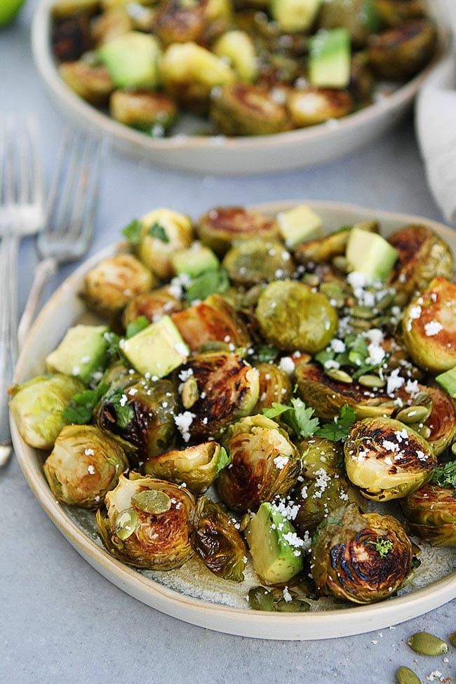 Roasted Brussels Sprouts With A Simple Honey Lime Dressing, Spiced Pepitas, Avocado, Cilantro, And A Sprinkling Of Cotija Cheese. This Easy Brussels Sprouts Recipe Is A Great Side Dish For The Holidays Or Any Day! #brusselssprouts #holiday #Christmas #Thanksgiving #sidedish #glutenfree #vegetarian #healthyrecipe Honey Lime Roasted Brussels Sprouts