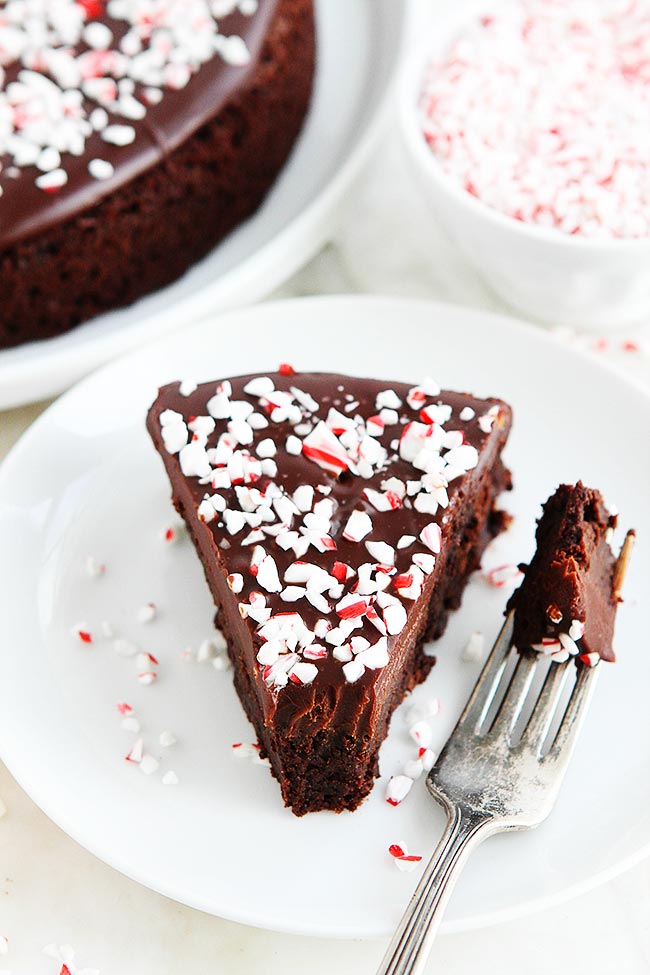 This Decadent Peppermint Flourless Chocolate Cake Is The Perfect Dessert For The Holiday Season. The Crushed Peppermint Candies Are The Perfect Finishing Touch To This Festive Gluten-Free Chocolate Cake. #cake #chocolatecake #glutenfree #dessert #Christmas #holidays #peppermint #mint #baking Peppermint Flourless Chocolate Cake on plate