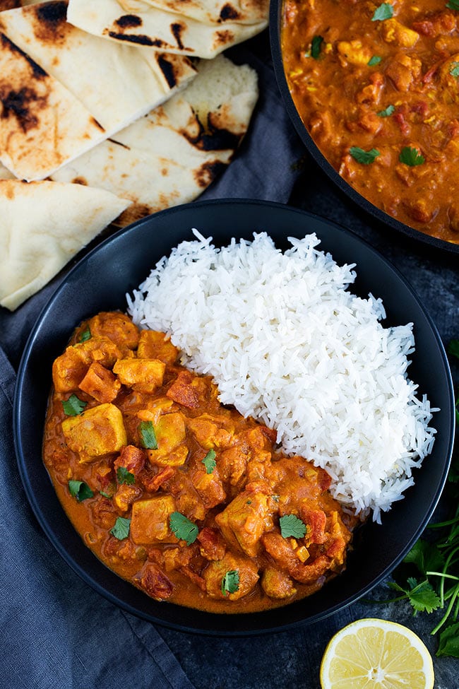 Chicken Tikka Masala in bowl with rice and naan on the side. 
