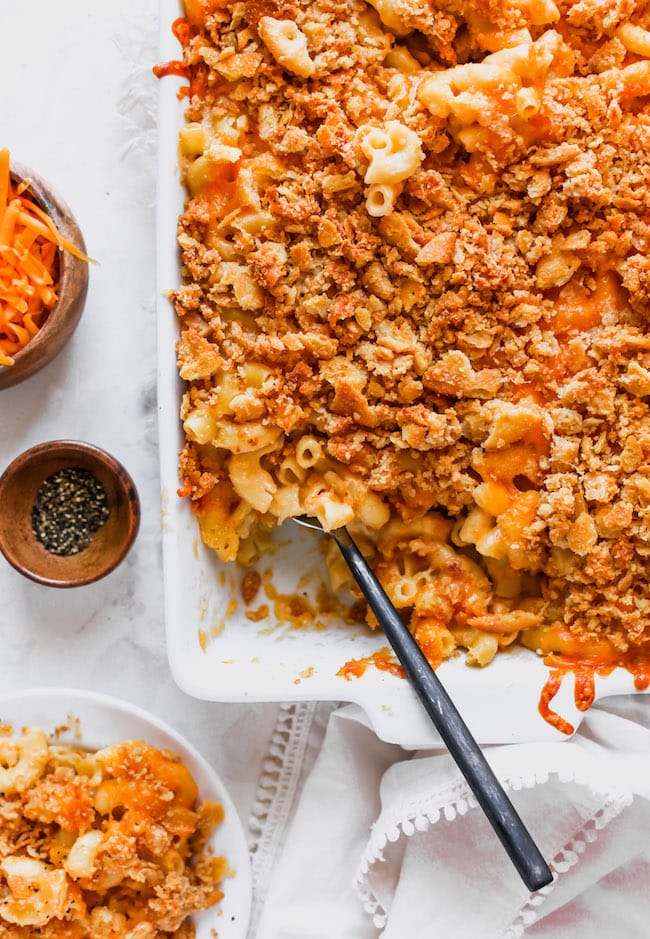 This Family Favorite Baked Mac And Cheese Is Creamy, Cheesy, And Finished With A Buttery Panko Cracker Topping. Serve As A Main Dish Or Side Dish, It Is The BEST Homemade Mac And Cheese Recipe! #macandcheese #bakedmacandcheese #macaroniandcheese #pasta #easyrecipe #kidfriendly #dinner #vegetarian #macaroni baked mac and cheese with cracker topping in pan with spoon.