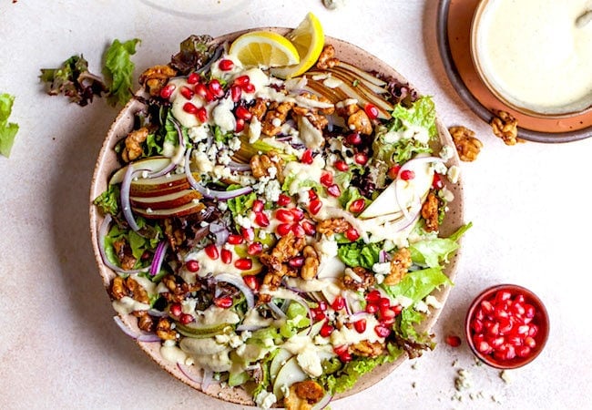 Pear salad in bowl with dressing on the side.