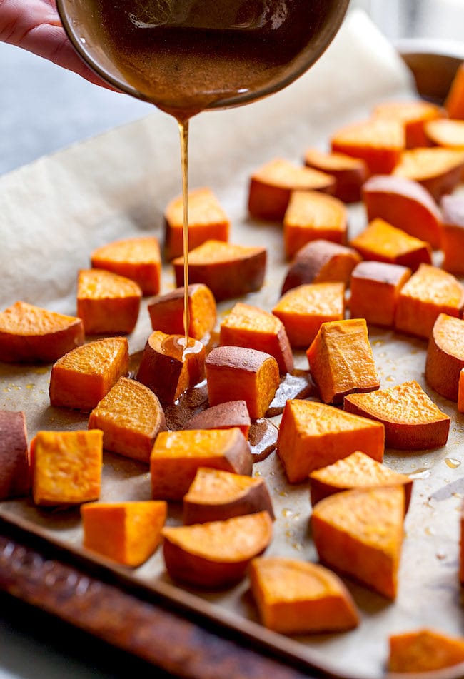 Maple being poured over cubed sweet potatoes. 